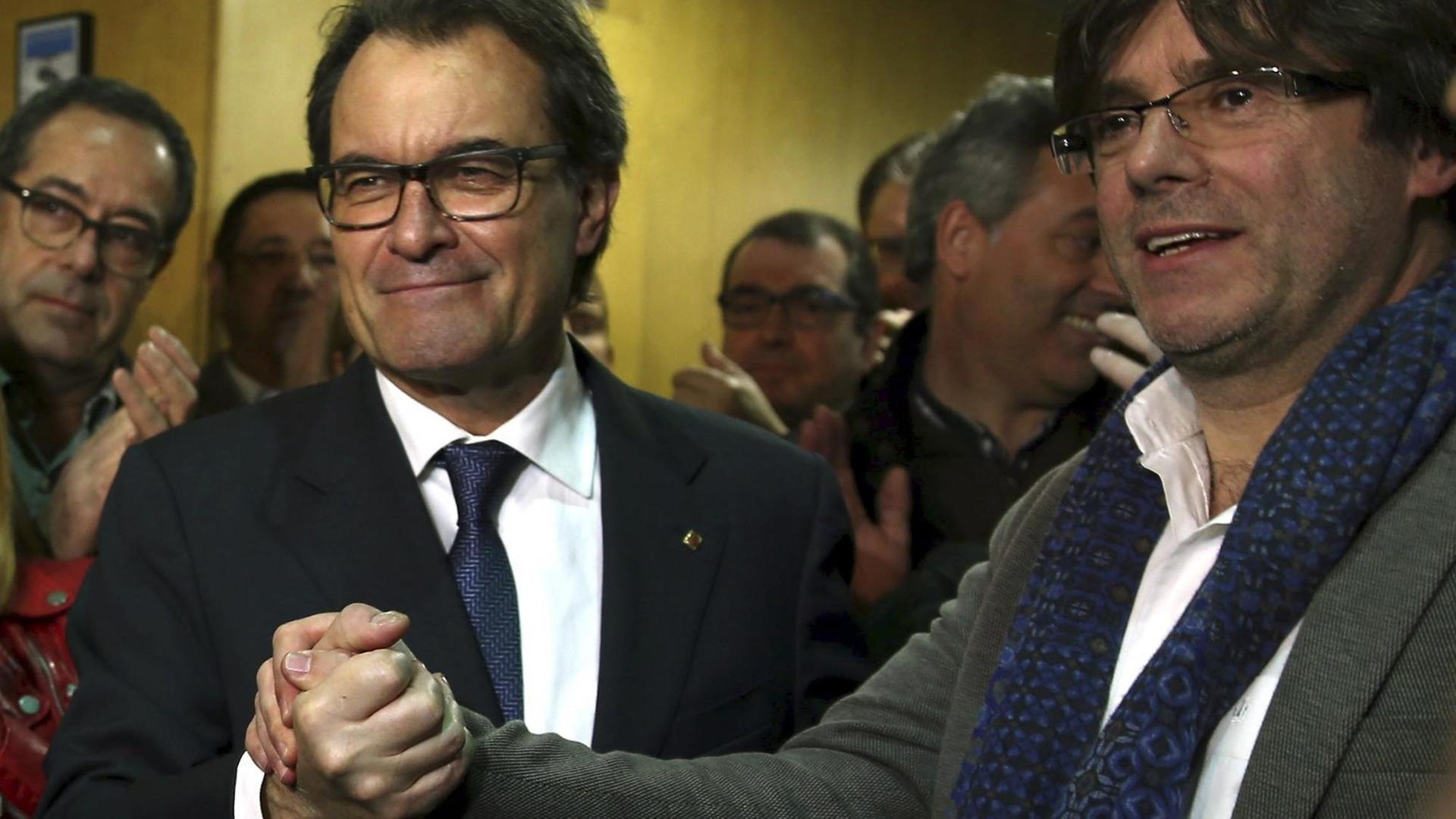 Kataloniens scheidender Ministerpräsident Artur Mas und sein designierter Nachfolger Carles Puigdemont geben sich die Hand.