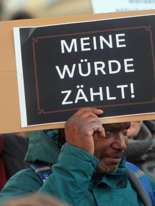 Ein dunkelhäutiger Mann hält während einer Demonstration ein Schild mit der Aufschrift "Meine Würde zählt" hoch.
