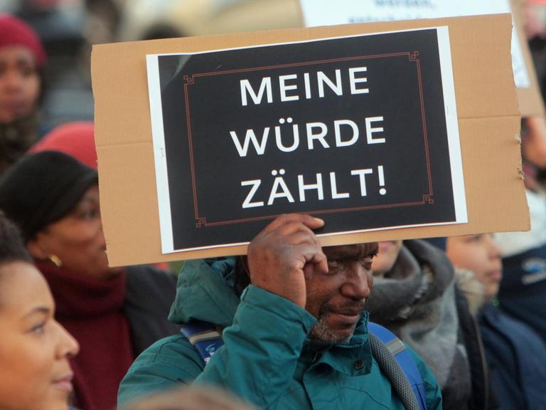Ein dunkelhäutiger Mann hält während einer Demonstration ein Schild mit der Aufschrift "Meine Würde zählt" hoch.