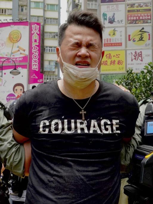 Ein Demonstrant wird in Hongkong von zwei Polizisten abgeführt. Auf dem T-Shirt des Verhafteten ist "Courage" zu lesen.