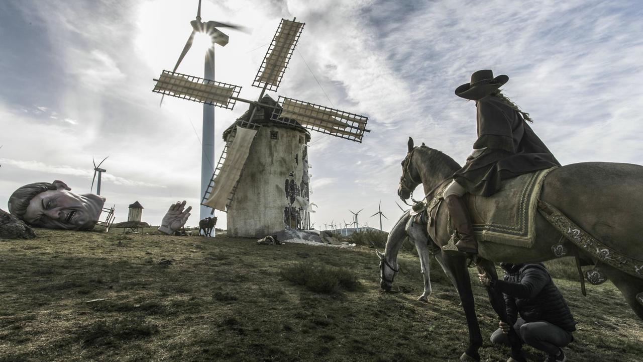 Eine Aufnahme von den Dreharbeiten zu "The Man Who Killed Don Quijote". Vor einer alten Windmühle. Dahinter moderne Windräder.