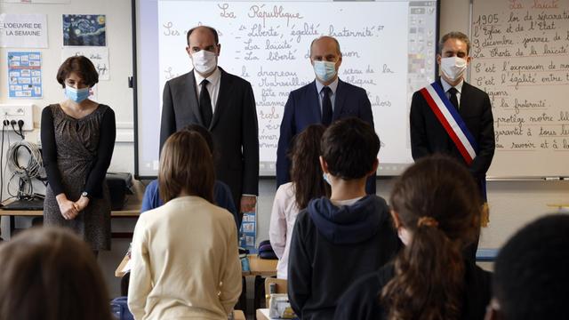 Der französische Premierminister Jean Castex, zweiter von links, und Bildungsminister Jean-Michel Blanquer, zweiter von rechts, halten eine Schweigeminute für den getöteten Geschichtslehrer Samuel Paty ab, am Montag, 2. November 2020, in einer Schule in Conflans-Sainte-Honorine, nordwestlich von Paris.