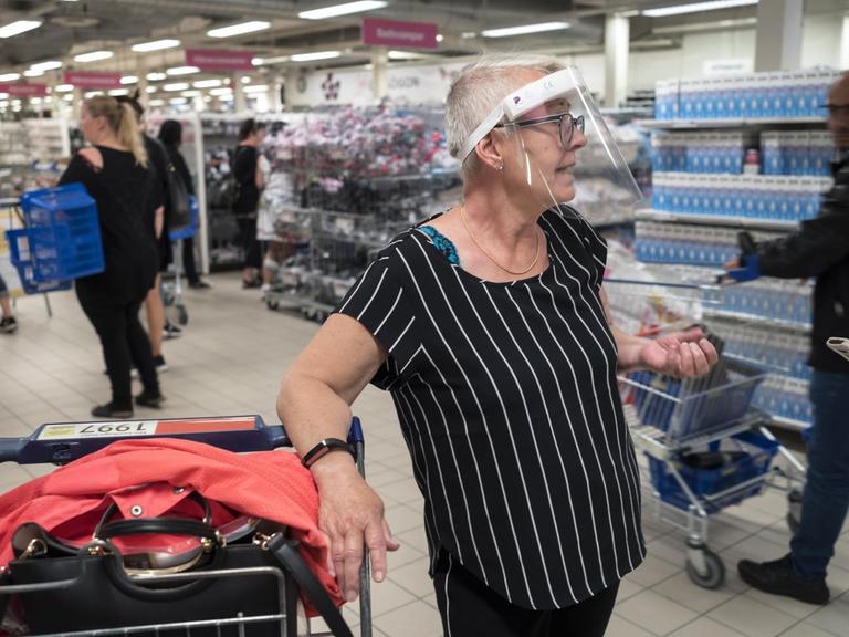 In einem Göteburger Supermarkt trägt eine ältere Frau ein Schutzvisier gegen eine mögliche Ansteckung mit dem Corona Virus.|