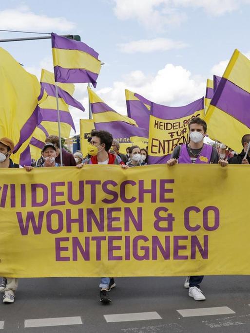 Demonstranten ziehen mit Fahnen und Bannern auf einer Straße entlang und fordern die Enteignung großer Wohnungskonzerne.