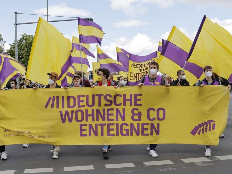 Demonstranten ziehen mit Fahnen und Bannern auf einer Straße entlang und fordern die Enteignung großer Wohnungskonzerne.