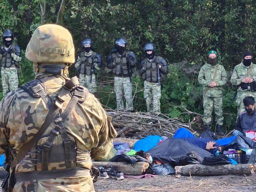 Polen, Migranten an der Grenze zu Belarus PODLASIE VOIVODESHIP, POLAND - AUGUST 20, 2021: Armed Polish soldiers and Afghan refugees who have fled the Taliban are seen near the village of Usnarz Gorny in eastern Poland on the border to Belarus. A group of 30 refugees have been stranded at the Polish-Belarusian border under the custody of Polish law enforcement officers for 12 days after illegally crossing the border. Armed members of Belarusian security forces do not let them return to Belarus while Polish border guards and army officers prevent them from continuing their journey across Poland. Irina Polina/TASS PUBLICATIONxINxGERxAUTxONLY TS10D123