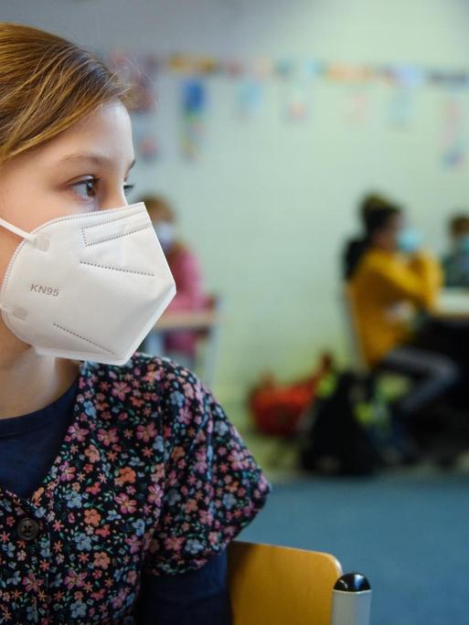 Eine Schülerin einer 4. Klasse sitzt im Unterricht an der Grundschule Russee in Kiel mit einer FFP-2-Maske an ihrem Platz. 