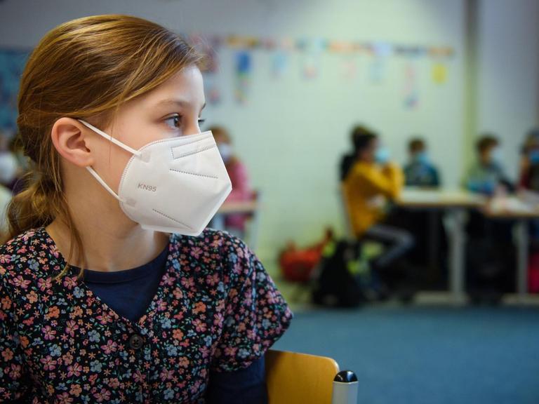 Eine Schülerin einer 4. Klasse sitzt im Unterricht an der Grundschule Russee in Kiel mit einer FFP-2-Maske an ihrem Platz. 