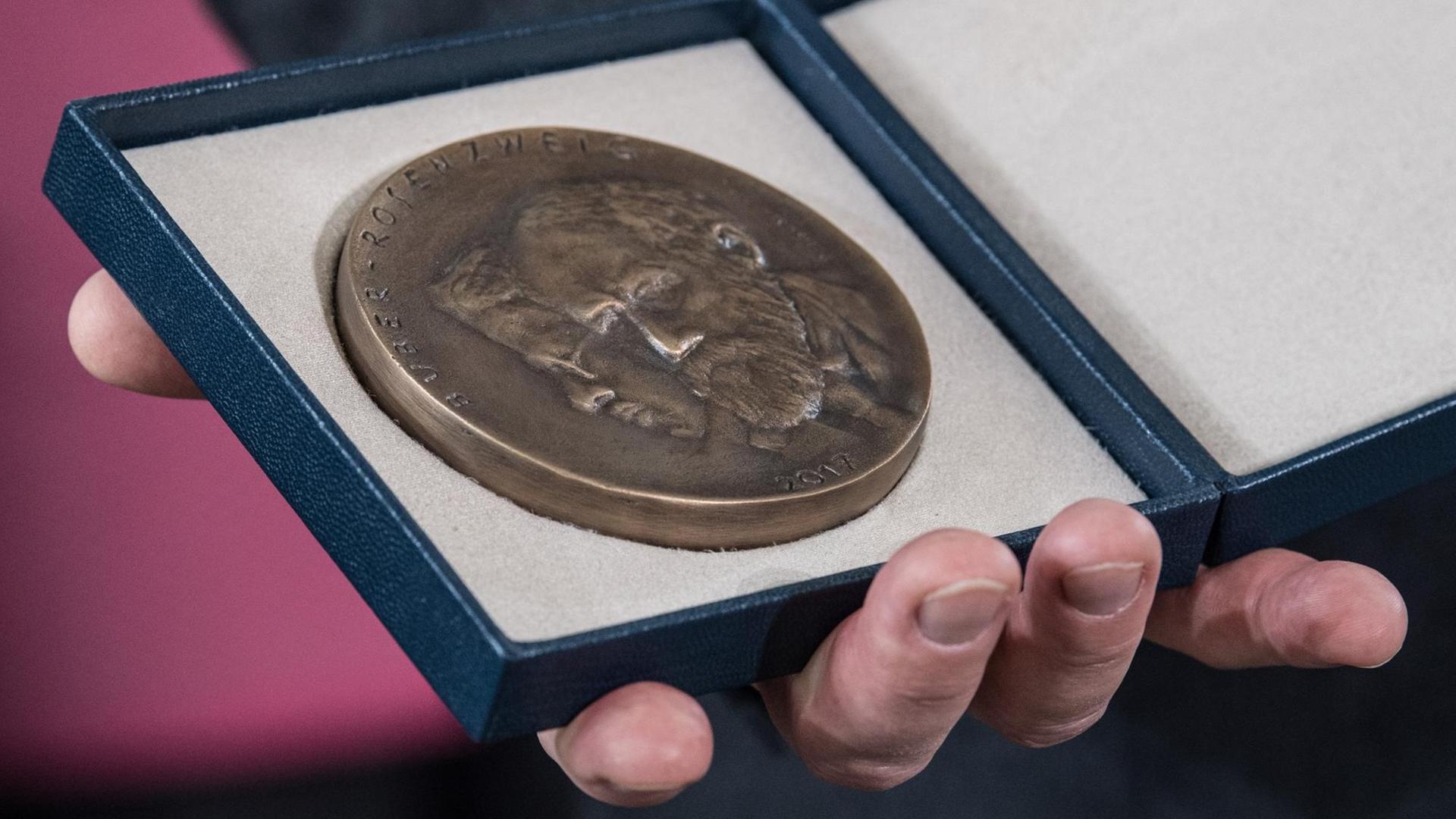 Eine Hand hält die Medaille in einem Etui mit den Konterfeis der jüdischen Philosophen Martin Buber und Franz Rosenzweig. Eine Hand hält die Medaille in einem Etui mit den Konterfeis der jüdischen Philosophen Martin Buber und Franz Rosenzweig.