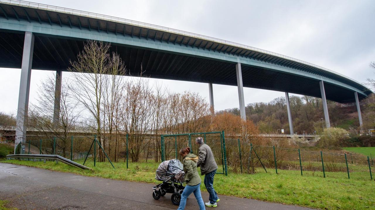 Spaziergänger laufen am 25.03.2016 unterhalb der Fechinger Talbrücke in Saarbrücken (Saarland). Die Brücke der Autobahn A6 ist wegen statischer Mängel bis mindestens Ende des Jahres gesperrt.