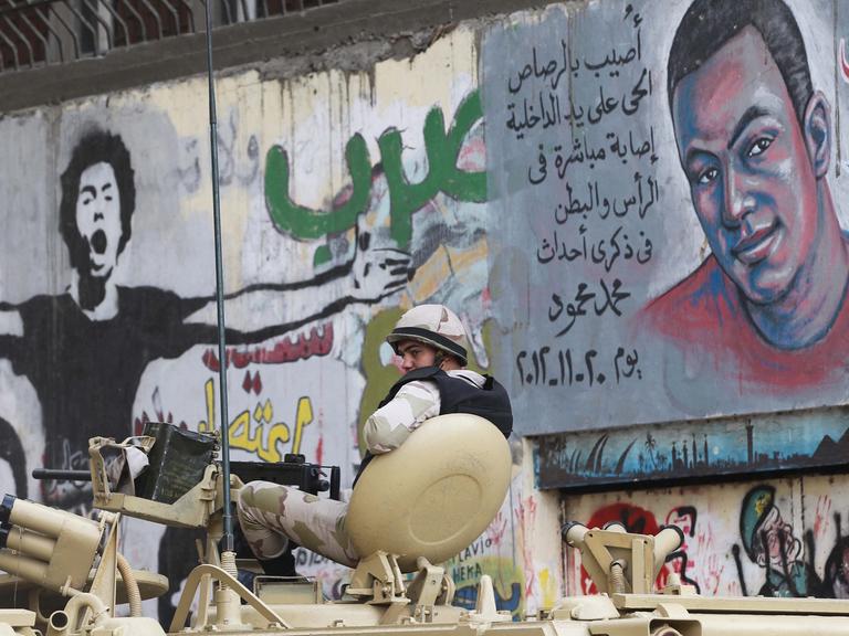 Ein ägyptischer Soldat vor einer Wand in Kairo, mit Graffits von Opfern gewaltsamer Zusammenstöße.