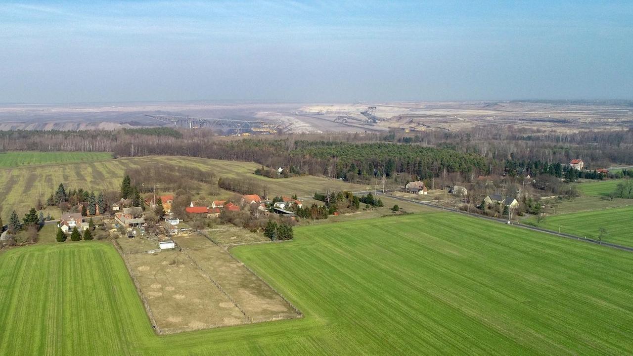 Eine Luftaufnahme auf das brandenburgisches Dorf Proschim, im Hintergrund ist eine riesige Braunkohlegrube zu sehen. 