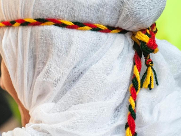 Ein Frau trägt ein Haarband in der Farben Kurdistans