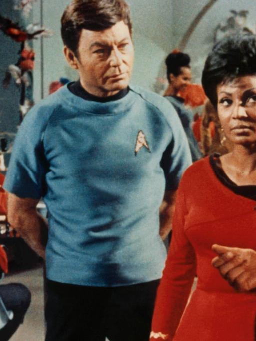 Szene aus der US-Fernsehserie "Star Trek" (1966-1969): Die Schwarze Schauspielerin Nichelle Nichols sowie die Schauspieler Leonard Nimoy, Deforest Kelley und William Shatner sprechen miteinander.