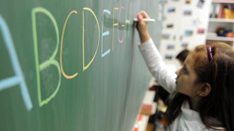 Eine Schülerin einer zweiten Klasse schreibt das ABC an die Tafel.