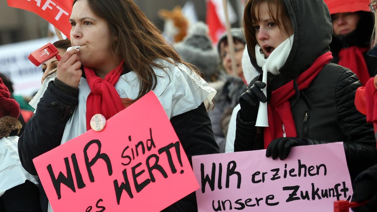 Zwei junge Frauen zeigen am 26.01.2017 in Berlin bei einem Streik der Berliner Erzieher und Sozialpädagogen Schilder mit der Aufschrift "Wir sind es wert" und "Wir erziehen unsere Zukunft, wir sind mehr wert!". 