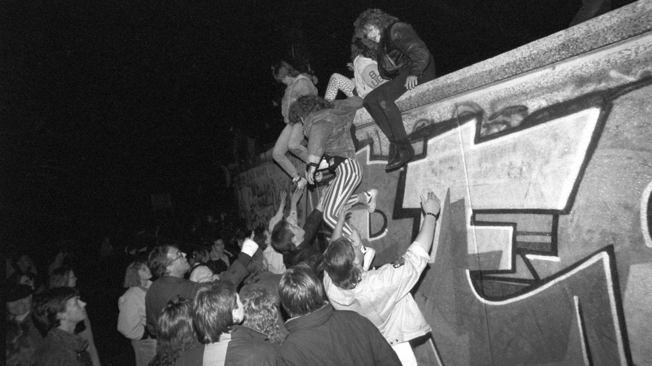 Menschen klettern am späten Abend des 09.11.1989 auf die Berliner Mauer am Brandenburger Tor. Am Abend des 09.11.1989 teilte SED-Politbüro Mitglied Günter Schabowski mit, daß alle DDR-Grenzen in die Bundesrepublik und nach West-Berlin für DDR-Bürger geöffnet werden. Daraufhin strömten binnen weniger Stunden tausende von Ost-Berlinern in den Westteil der Stadt, wo es zu volksfestartigen Verbrüderungen zwischen Bürgern aus Ost- und Westdeutschland kam | Verwendung weltweit