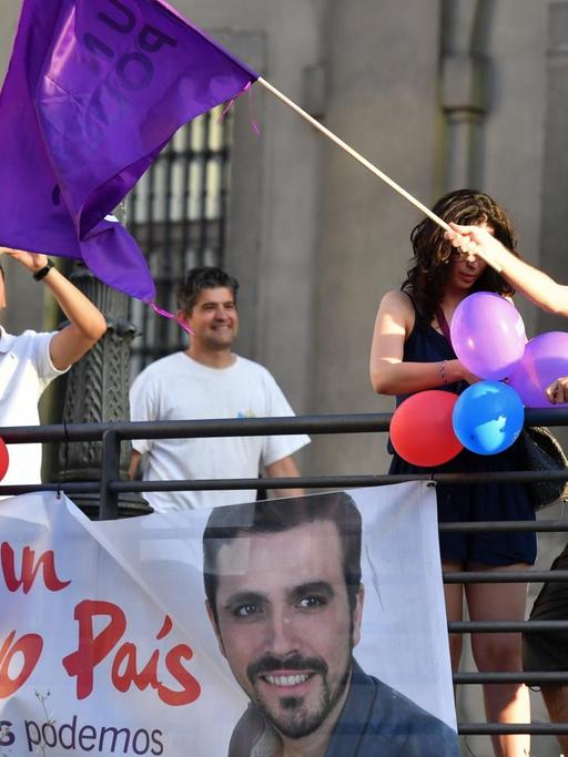 Ein Anhänger der linken Podemos-Partei schwenkt am Wahltag in Madrid eine Fahne.