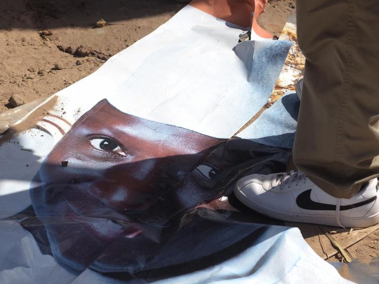 Ein Fuß steht auf dem am Boden liegenden Wahlplakat des abgewählten gambischen Präsidenten Jammeh.
