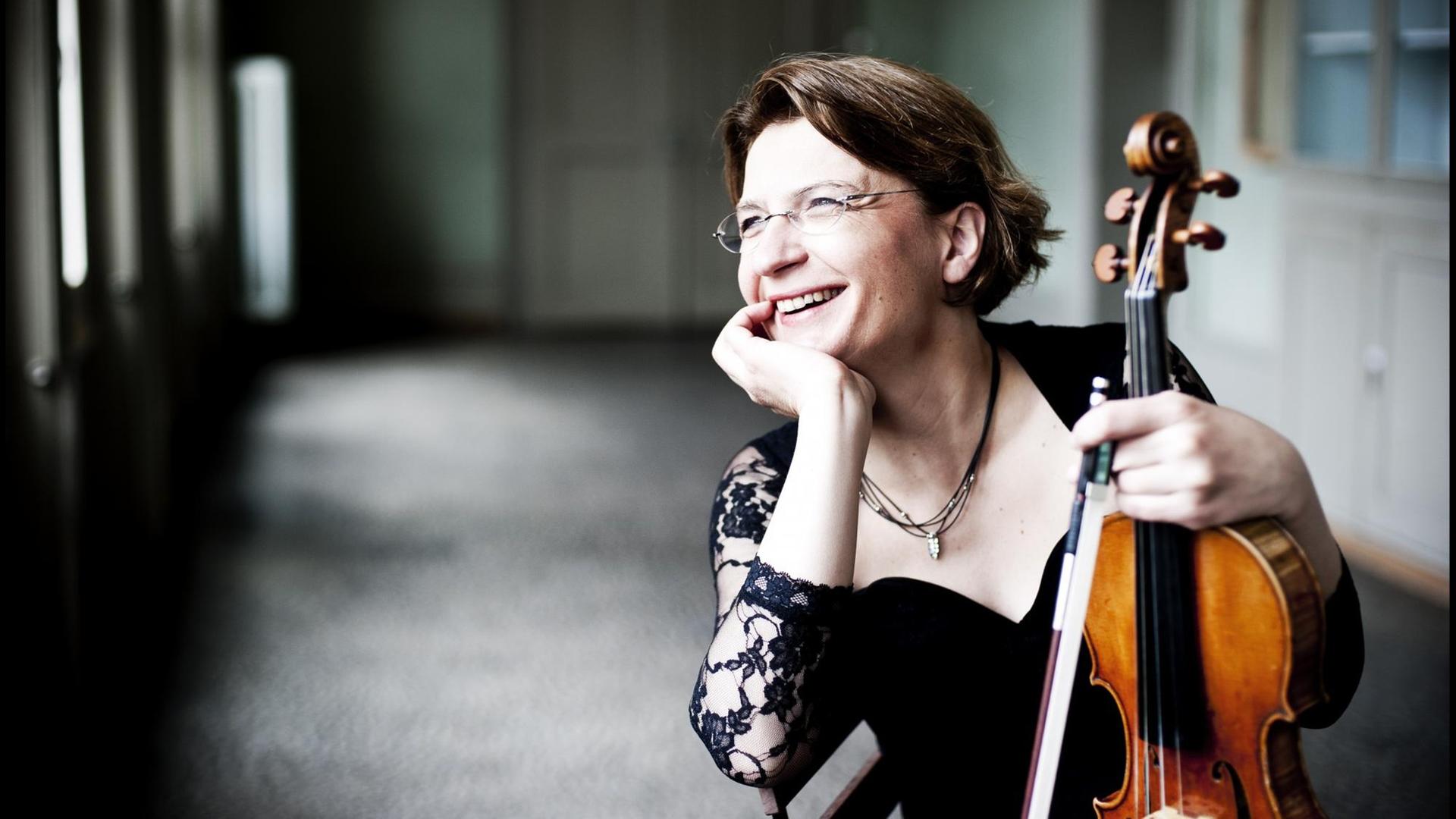 Die Musikerin Antje Weithaas sitzt mit ihrer Violine in einem Raum