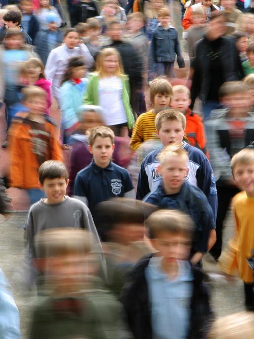 Viele Grundschülerinnen und Grundschule tanzen auf einem Schulhof.