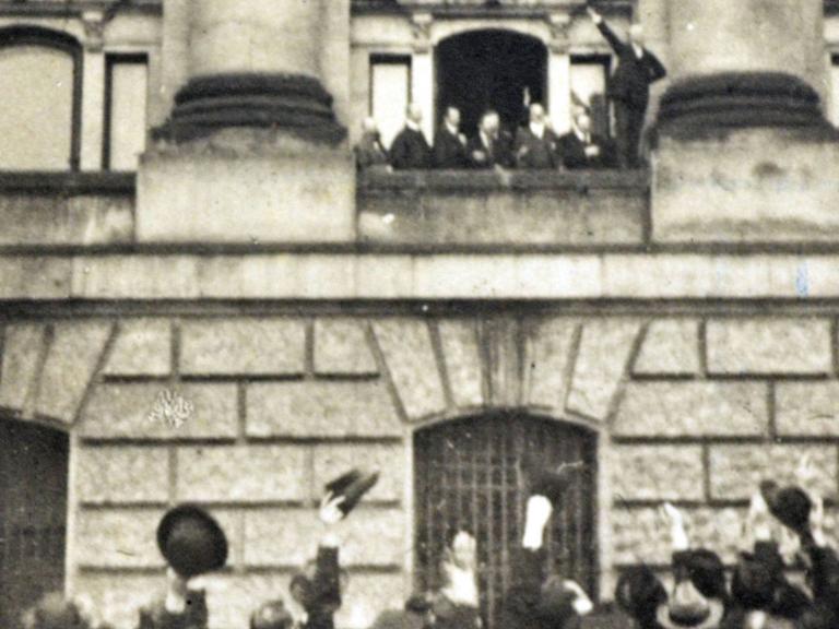 Menschen jubeln vor dem Balkon des Reichstagsgebäudes