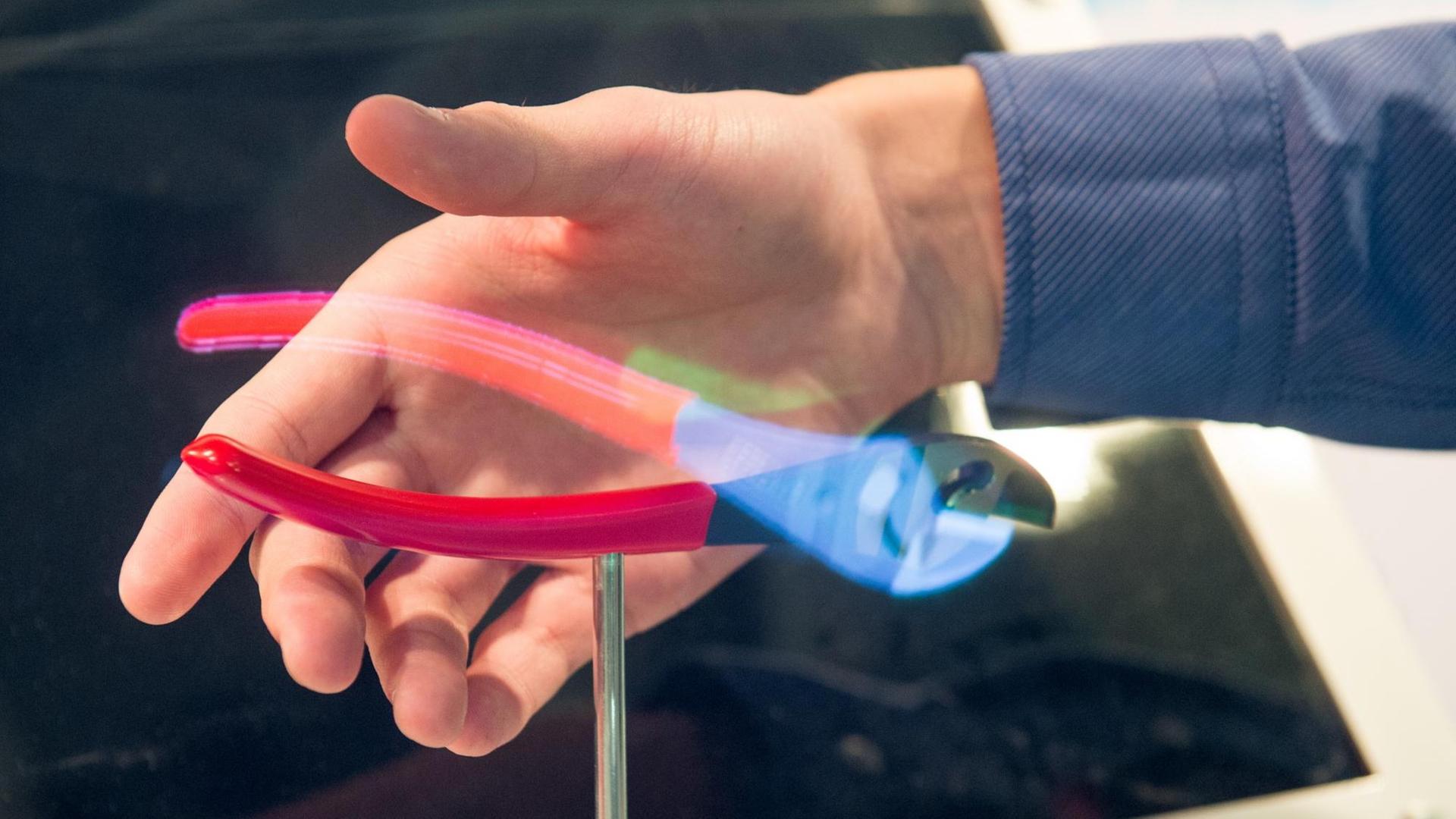 Thomas Gerbracht aus Wuppertal demonstriert die von ihm entwickelte holografischen Projektion. Eine halbe Zange ist auf einem Podest montiert, die andere wird rein optisch als Hologramm ergänzt.