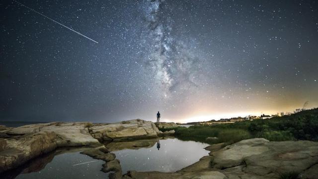 "Sternzeit" im Deutschlandfunk: Das Motiv zur Sendung zeigt einen Menschen vor einem Sternenhimmel, auf dem eine Sternschnuppe zu sehen ist.