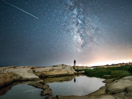 "Sternzeit" im Deutschlandfunk: Das Motiv zur Sendung zeigt einen Menschen vor einem Sternenhimmel, auf dem eine Sternschnuppe zu sehen ist.