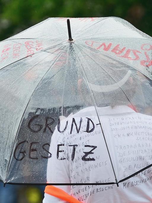 Teilnehmerin einer "Corona-Leugner" Demonstration in Heidelberg. Sie hält einen mit den Worten "Grundgesetz" und "Widerstand" beschriebenen Regenschirm.