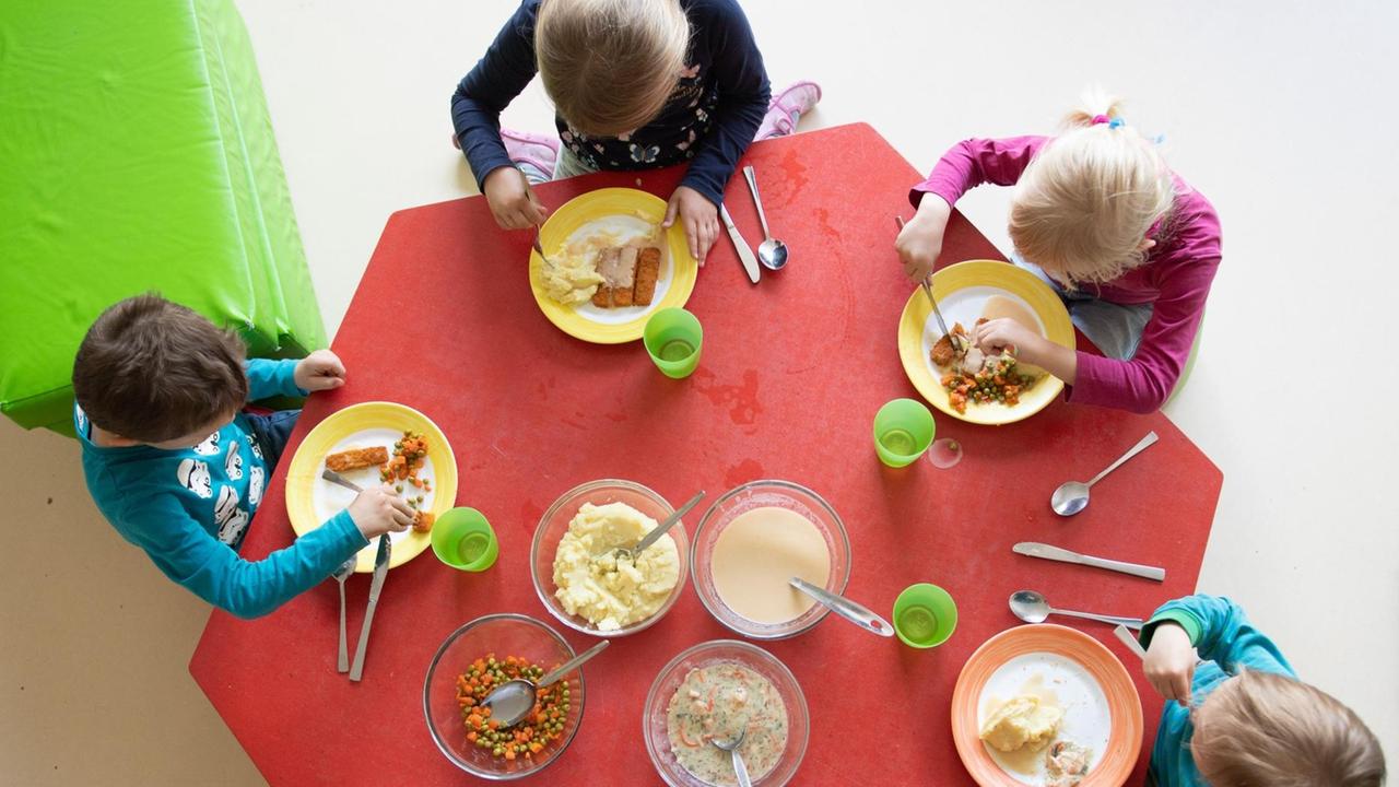 Kinder sitzen im Rahmen der Notbetreuung in einem Kindergarten in Sachsen während des Mittagessens an einem Tisch. 