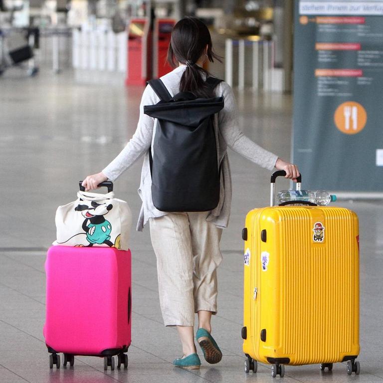 Eine einsame Reisende mit zwei großen Koffern menschenleeres Terminal 1 in der Abflughalle B im Flughafen Frankfurt, Hessen, Deutschland