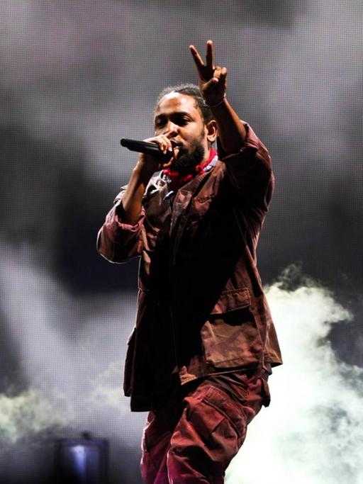 Kendrick Lamar beim Panorama Music Festival 2016 in New York. Der Musiker steht vor dunklem Hintergrund und macht mit einer Hand das Peace-Zeichen