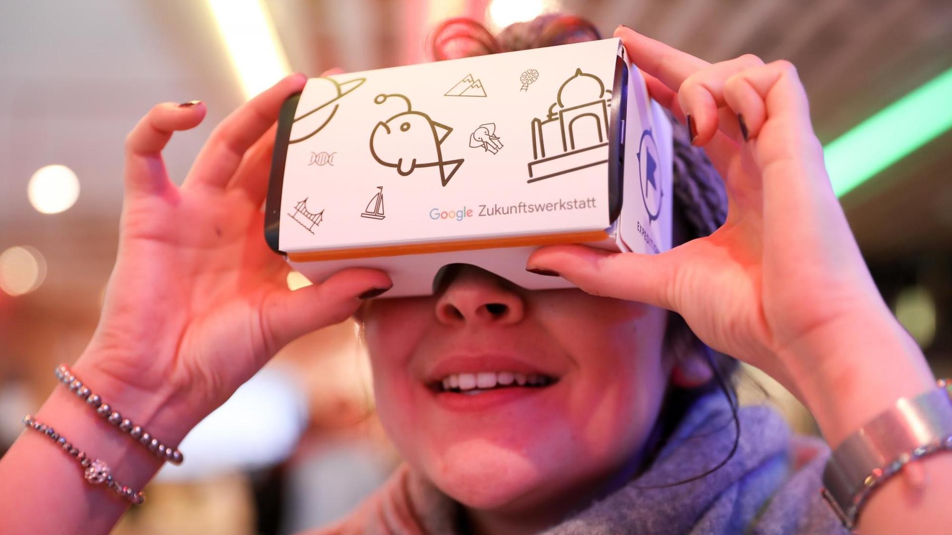 20.03.2018, Hamburg: Eine junge Frau schaut vor einer Pressekonferenz zur Google Zukunftswerkstatt Hamburg in eine VR-Brille von Google. Lehrer und Schüler, Berufstätige und Gründer sollen bei Google in Hamburg fitter für die Codes und Digitalisierung von Morgen werden.