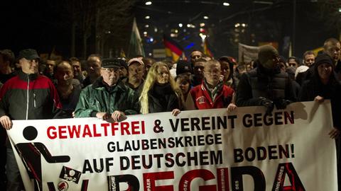 Mehrere Pegida-Demonstranten halten ein Banner mit der Aufschrift "Gewaltfrei und vereint gegen Glaubenskriege auf deutschem Boden!"