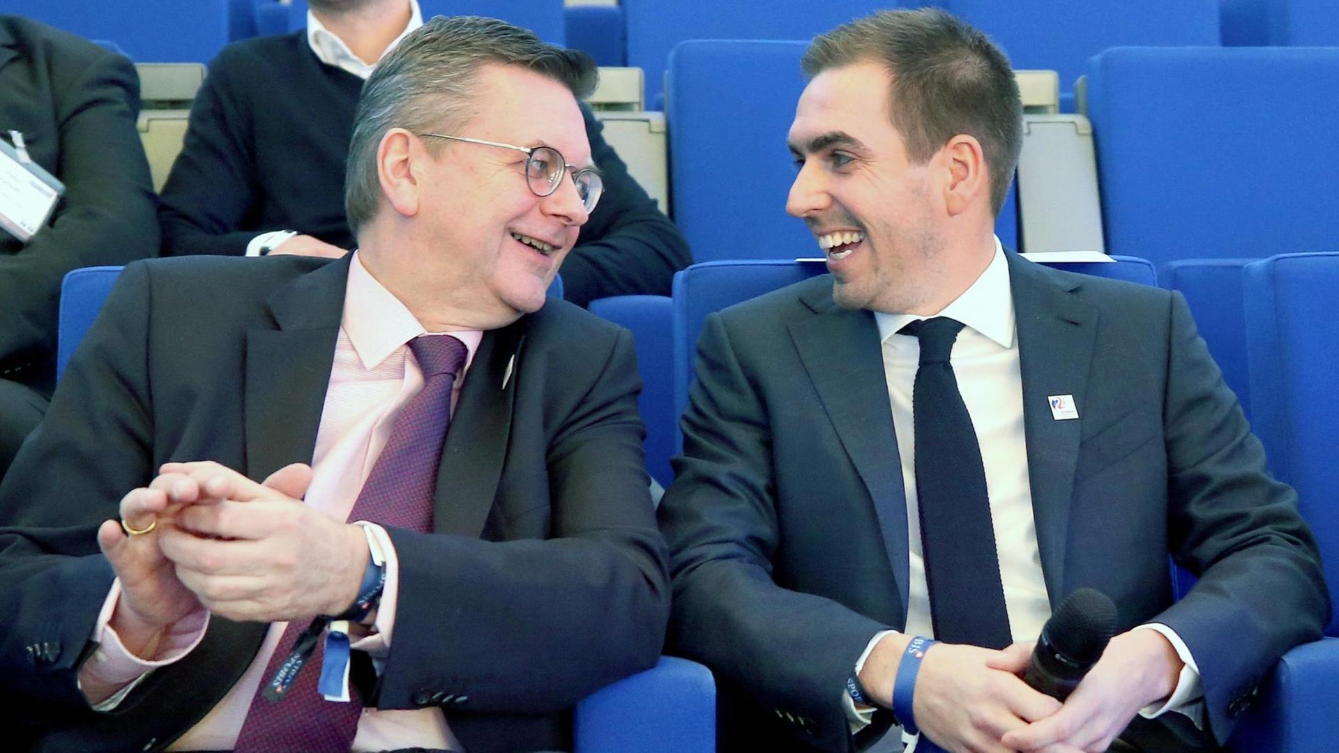 Reinhard Grindel (l), Präsident des Deutschen Fußball-Bundes (DFB), und der ehemalige Fußball-Nationalspieler Philipp Lahm unterhalten sich vor Beginn einer Talkrunde auf dem Sportbusiness-Kongress SpoBis.