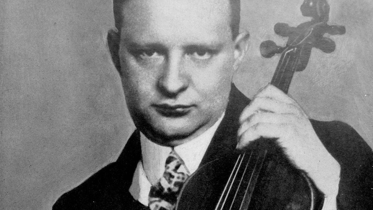 Ein Mann präsentiert auf einem Schwarz-weiß-Foto sein Streichinstrument.