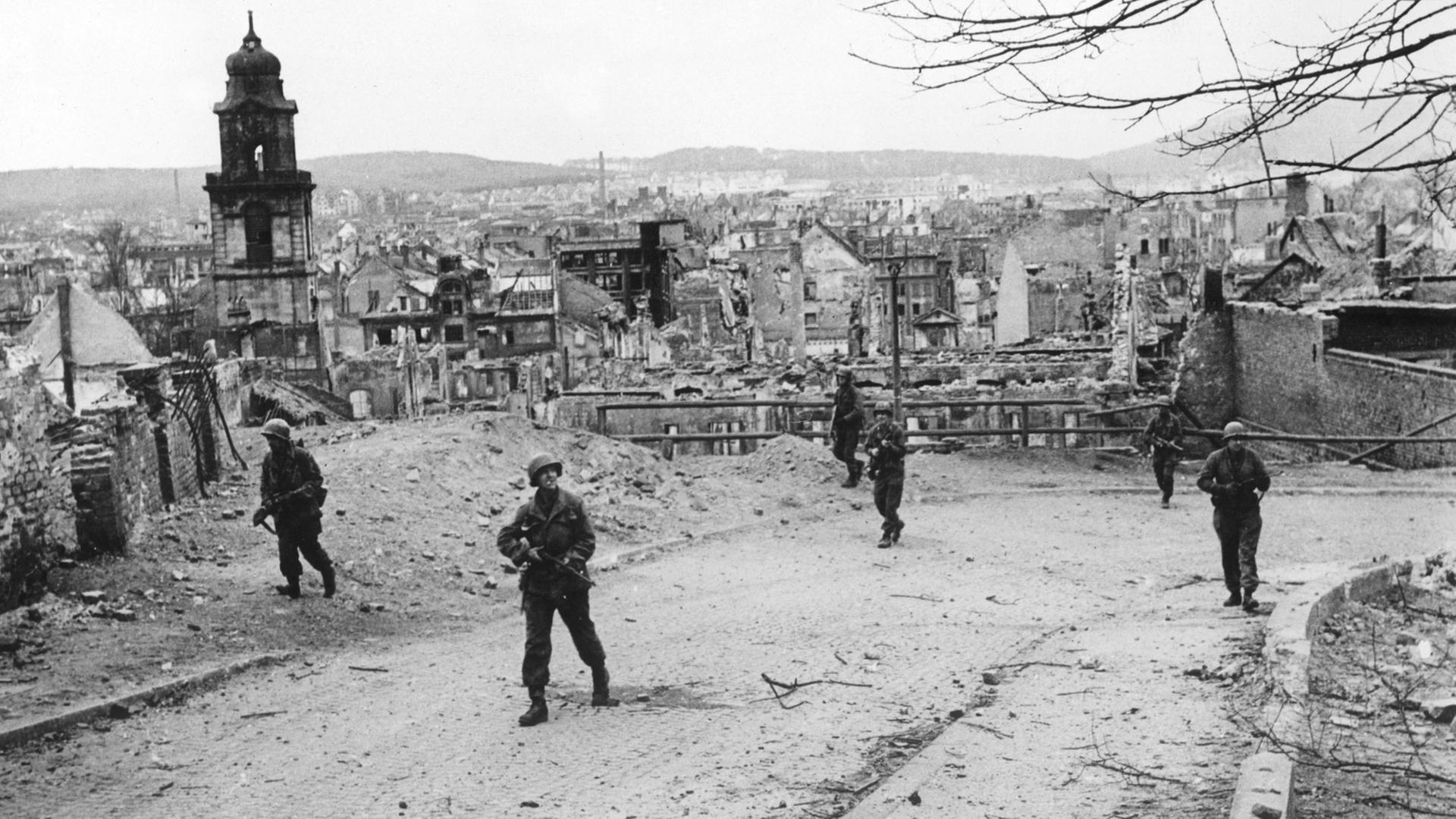 Soldaten der 70. Division der 7. US-Armee gehen am 20.03.1945 durch das zerstörte Saarbrücken. Die Stadt wurde durch Luftangriffe und Artilleriegeschütze in Trümmern gelegt und am 20.03.1945 von US-Truppen eingenommen.