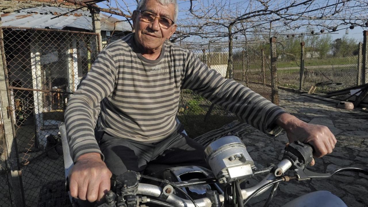 Ein älterer Mann sitzt stolz auf seinem Motorrad