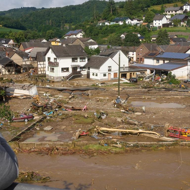 Eine Frau blickt auf die Zerstörungen in einem Ort im Kreis Ahrweiler am Tag nach dem Unwetter. Mindestens sechs Häuser wurden durch die Fluten zerstört.
