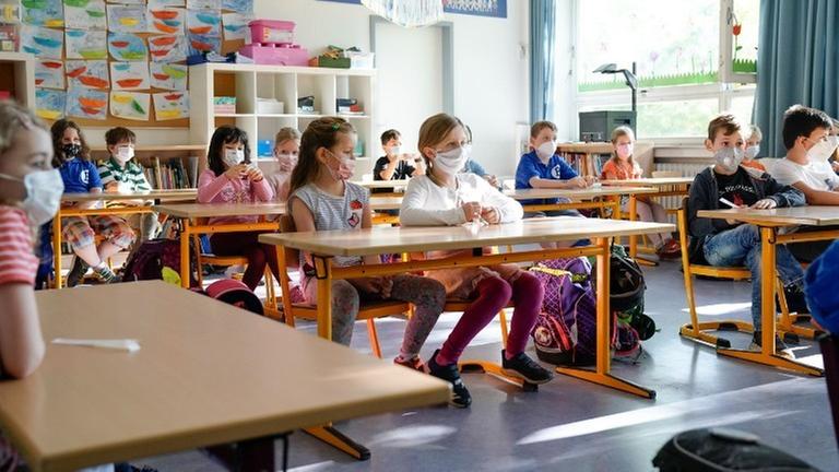 Grundschulkinder sitzen in einem sonnendurchfluteten Klassenraum an ihren Tischen. Grundschulkinder sitzen in einem sonnendurchfluteten Klassenraum an ihren Tischen.