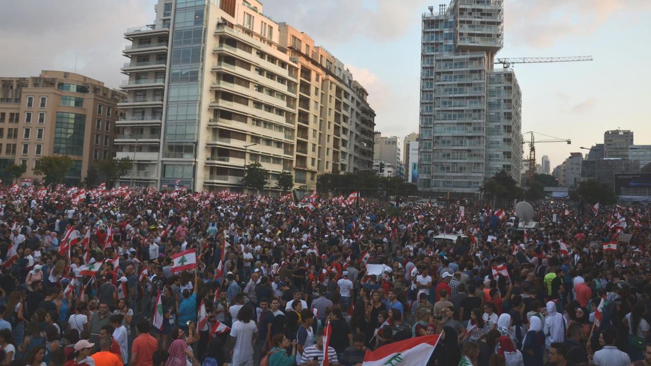 Partystimmung bei den großen Protesten in Beirut seit knapp zwei Wochen gegen die Regierung. Hunderttausende mit Flaggen stehen vor Hochhäusern.