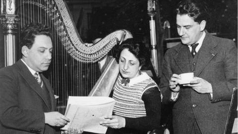 Drei Musiker um eine Harfe versammelt