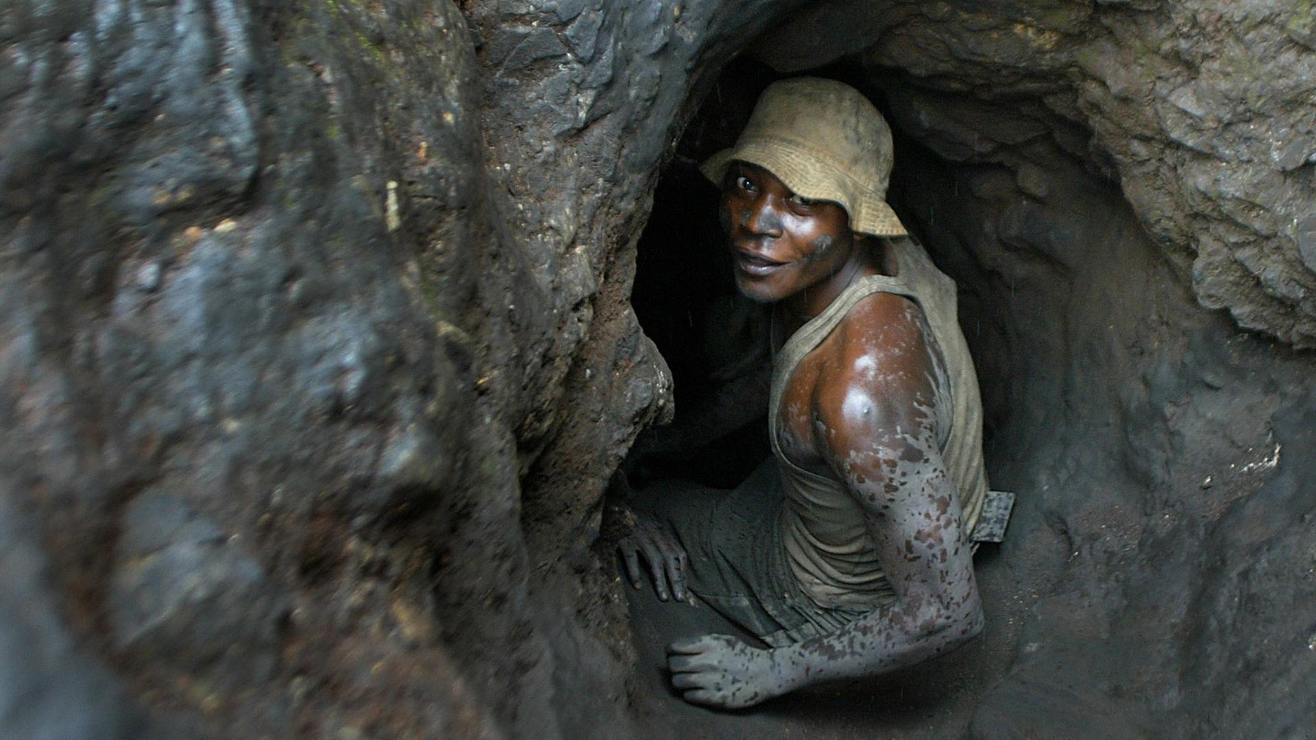 Im Kongo klettert ein Mann in eine enge Mine um Kobalt abzubauen
