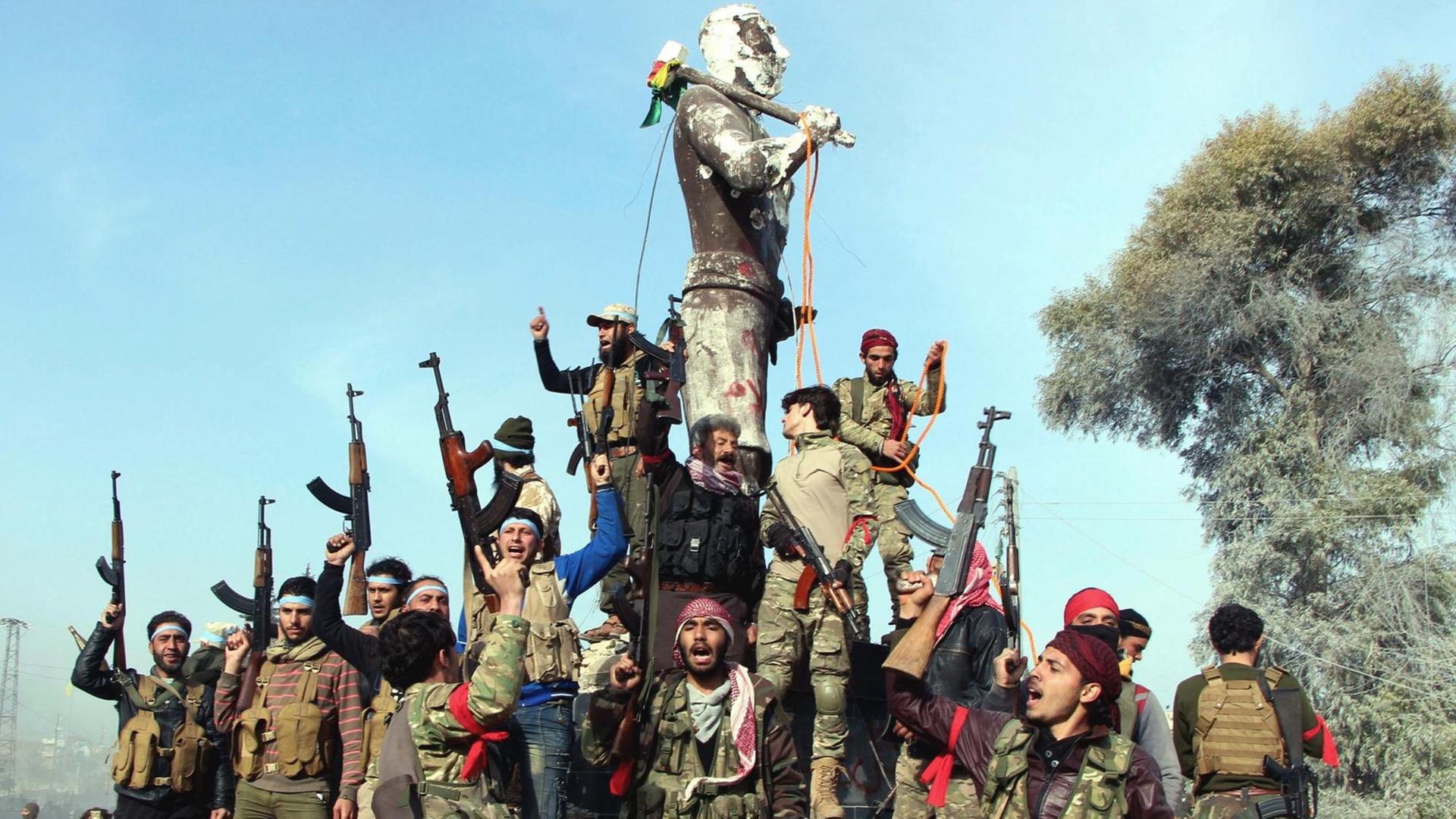 Soldaten der mit der türkischen Armee verbündeten oppositionellen Freien Syrischen Armee feiern im Zentrum von Afrin an der Statue einer mythologischen kurdischen Figur.