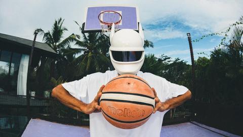 Cro trägt einen weißen Helm und hält einen Basketball in den Händen.