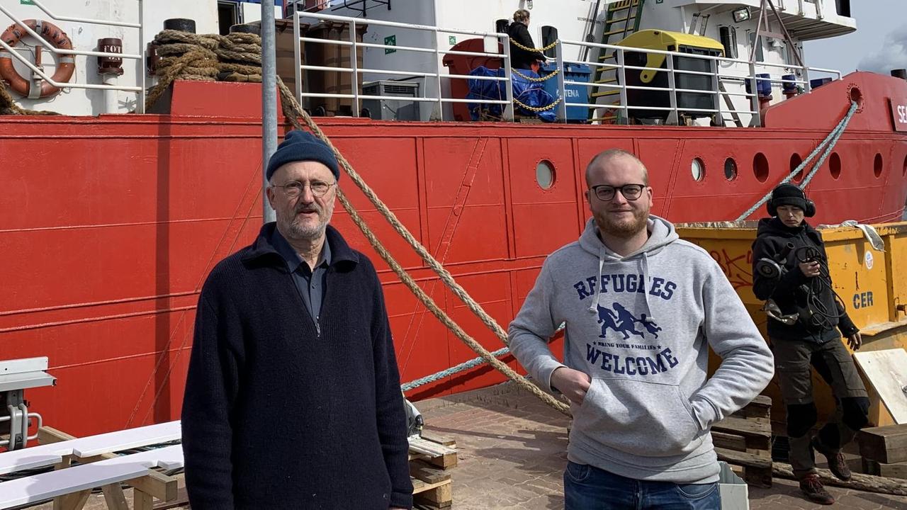 Bischof em. Michael Wüstenberg (links) und Koordinator Kay Echelmeyer stehen vor der Sea-Eye 4 im Rostocker Hafen. 