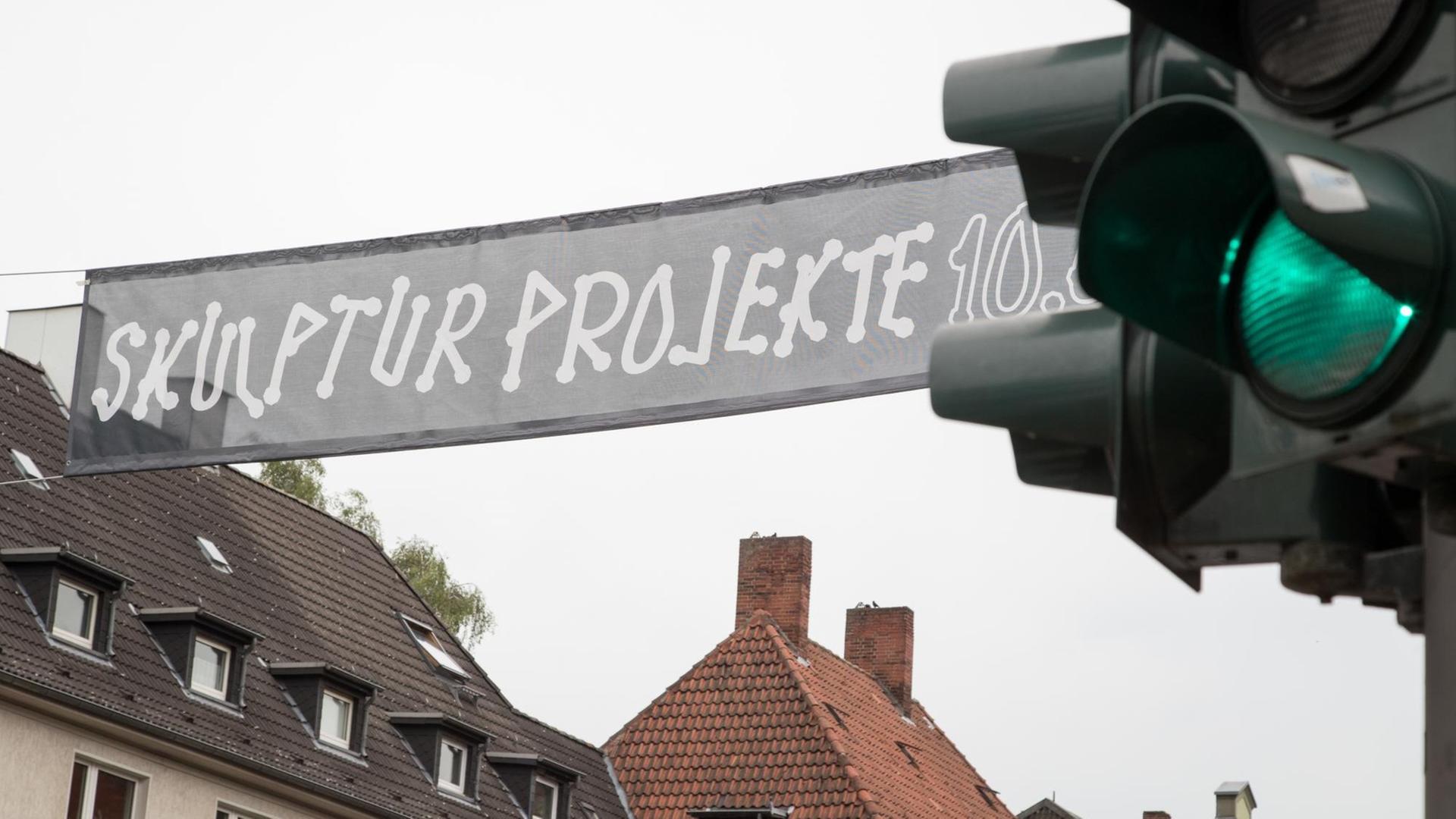 "Skulptur Projekte" steht auf einem Transparent am 09.06.2017 hinter einer grünen Verkehrsampel in Münster (Nordrhein-Westfalen). Die Eröffnung der fünften Ausgabe der Zehn-Jahres-Großausstellung Skulptur Projekte ist am 10.06.2017. Ihr Ableger ist im 60 Kilometer von Münster entfernten Marl.