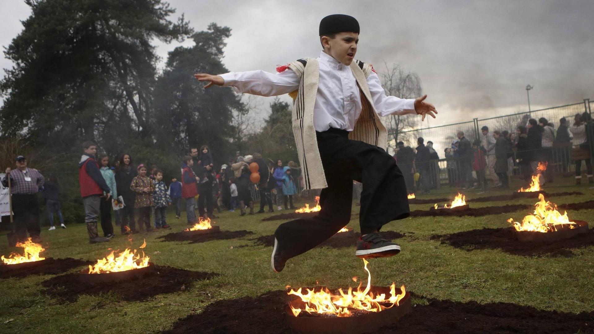 Ein Junge springt bei den Feierlichkeiten zum Persischen Neujahr über ein Lagerfeuer. Das Bild ist bei Feierlichkeiten der Iranischen Community in Vancouver, Kanada aufgenommen.