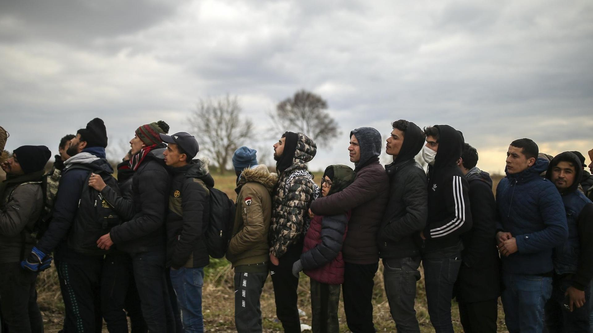 Flüchtlinge harren hinter einem Stacheldrahtzaun an der griechisch-türkischen Grenze aus